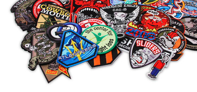 Pile of custom embroidered patches showing variety of shapes, sizes, and edge styles